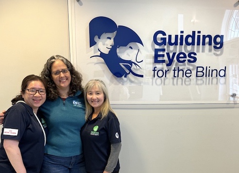 Meicy, Clover and Ivy pose at lobby Guiding Eyes sign