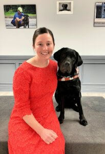 Jessica and black Lab guide dog Valise sit for their team portrait
