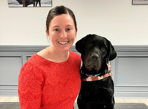 Jessica and black Lab guide dog Valise sit for their team portrait
