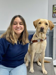 Sofia and yellow Lab guide Kay sit for their team portrait