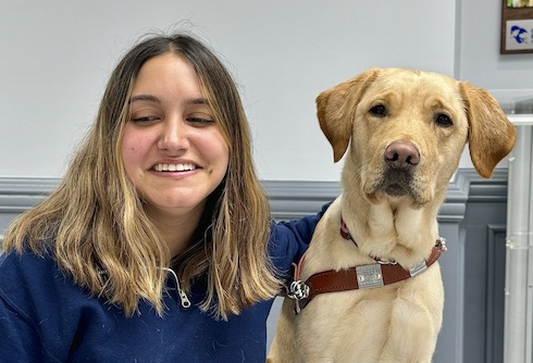 Sofia and yellow Lab guide Kay sit for their team portrait