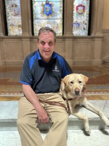 Carl and yellow Lab Dayton sit at the stained windows of the State House in Boston