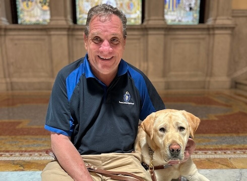 Carl and yellow Lab Dayton sit at the stained windows of the State House in Boston