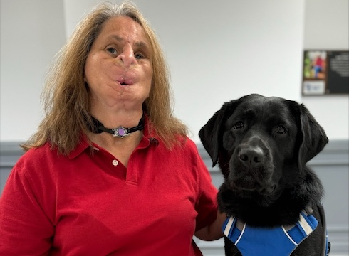 Catie sits with black lab guide dog Winette for their team portrait