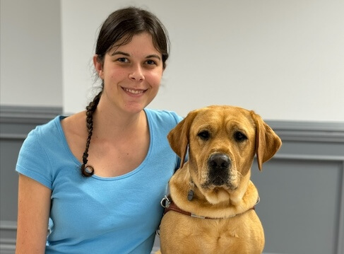 Sarah and yellow Lab guide dog Heron sit for their team portrait