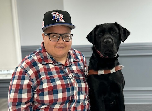 Gloria and black lab Elsie sit side by side for their team portrait