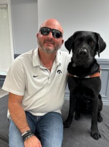 Anthony and his black Lab guide dog sit side by side for their team portrait