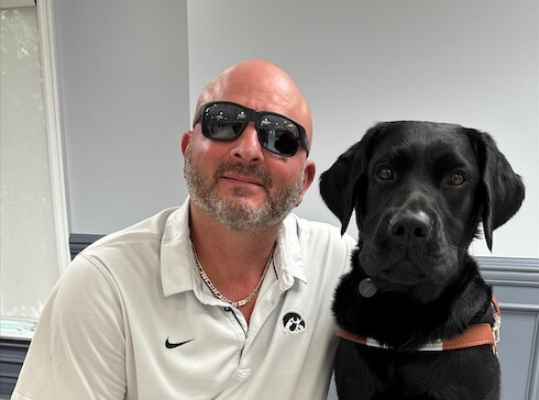 Anthony and his black Lab guide dog sit side by side for their team portrait
