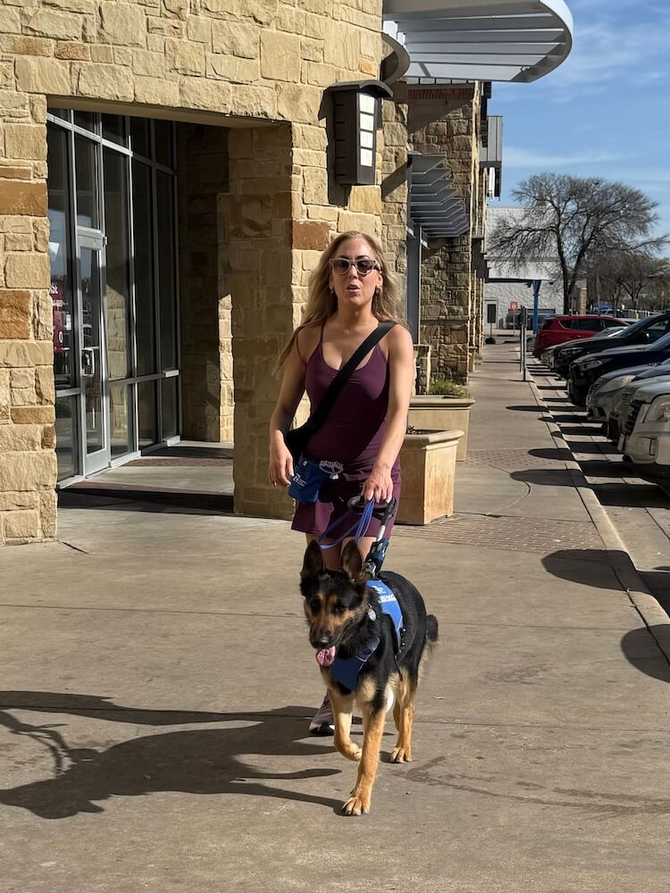 Irma walks with her guide dog Wonder, a German Shepherd through a business area