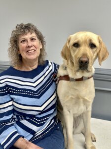 Andrea and her yellow Lab guide dog Ambie sit together for their team portrait