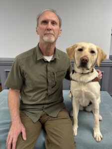 Mike and his yellow Lab guide dog Koi sit together for their team portrait