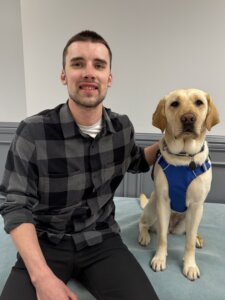 Alex and his yellow Lab guide dog Marina sit together for their team portrait
