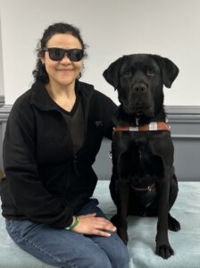 Floss and black Lab guide dog Neil sit side by side for their team portrait