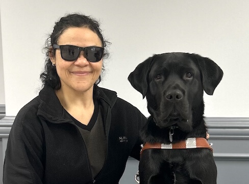 Floss and black Lab guide dog Neil sit side by side for their team portrait