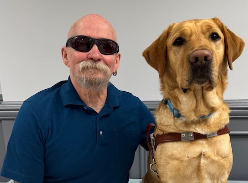 Jerry and his yellow Lab guide dog Elias sit head to head for their graduate portrait