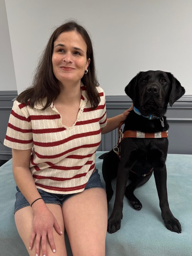 Maddie and black Lab guide dog Jackie sit side by side for their team portrait