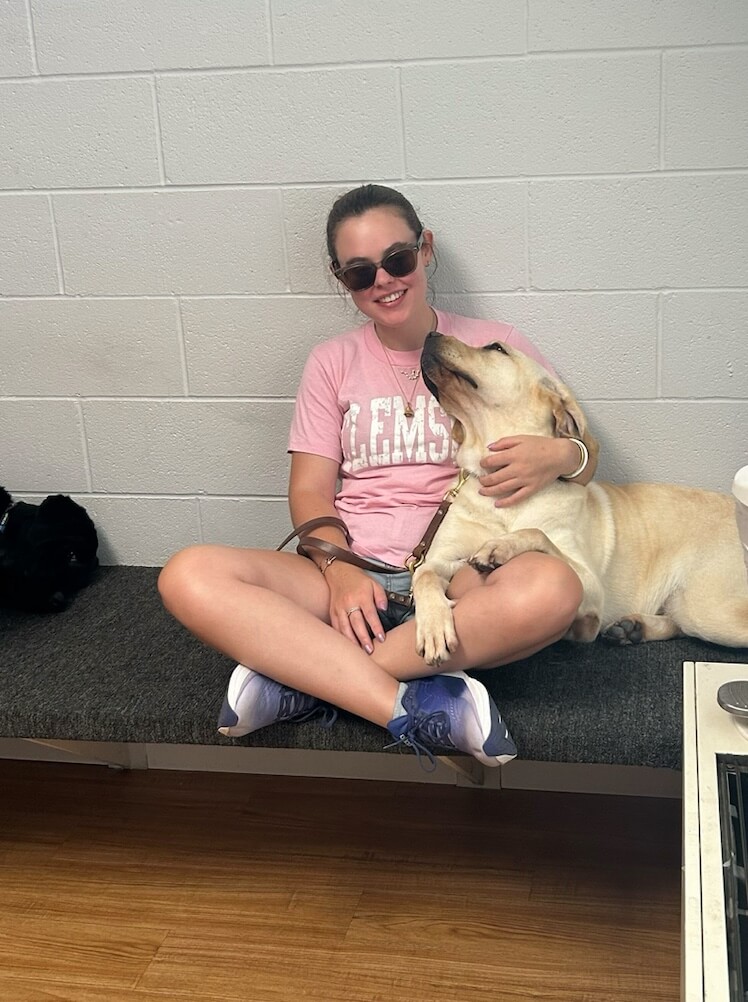 Ashlee sits crosslegged on the grooming bench with arm around Dream who looks up to her lovingly