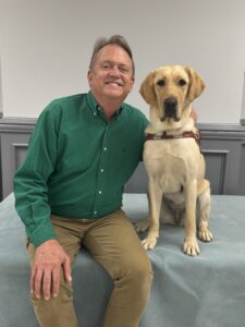 George sits beside yellow Lab guide dog Whispy for their team portrait