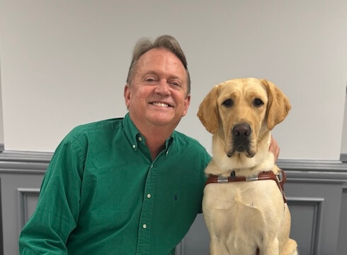 George sits beside yellow Lab guide dog Whispy for their team portrait