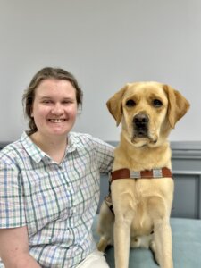 Lillian sits beside yellow Lab guide dog Ozark for their team portrait