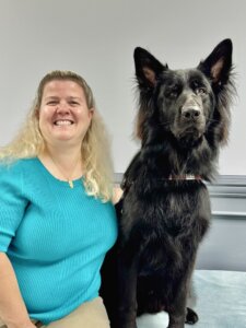 Sharon sits next to her black German Shepherd guide dog Stephen, who's ears tower above for the team portrait.