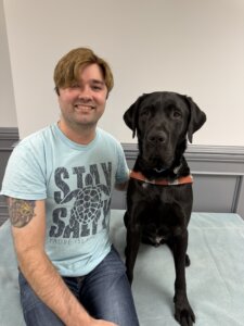Dillon and black Lab guide dog Alonzo sit side by side for their team portrait