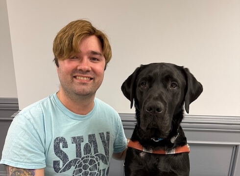 Dillon and black Lab guide dog Alonzo sit side by side for their team portrait