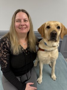 Liz and yellow Lab guide dog Omaha sit side by side for their team portrait