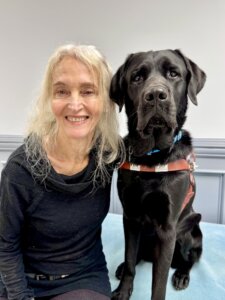 Hillary and black Lab guide dog Essex sit side by side for their team portrait
