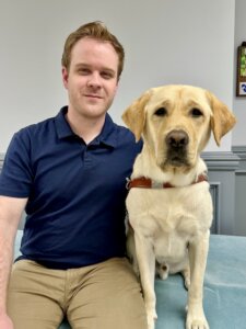 James and yellow Lab guide dog Hogan sit close together for their team portrait