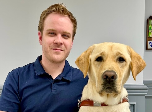 James and yellow Lab guide dog Hogan sit close together for their team portrait