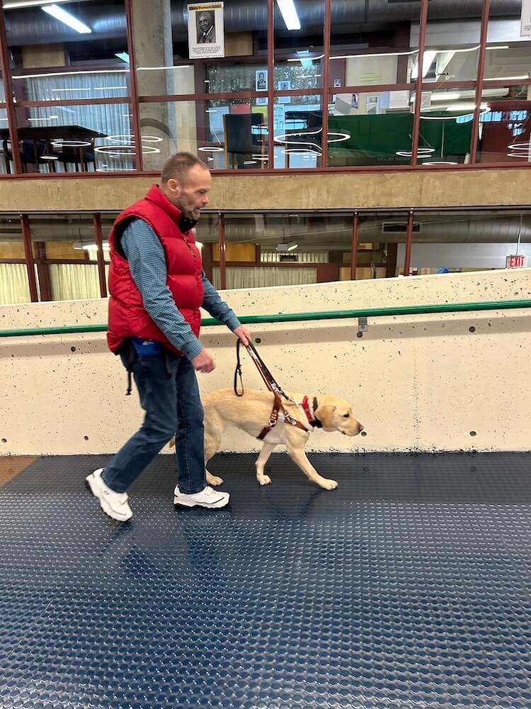 Juliet leads Jack up a long ramp adjacent to a multi floored building