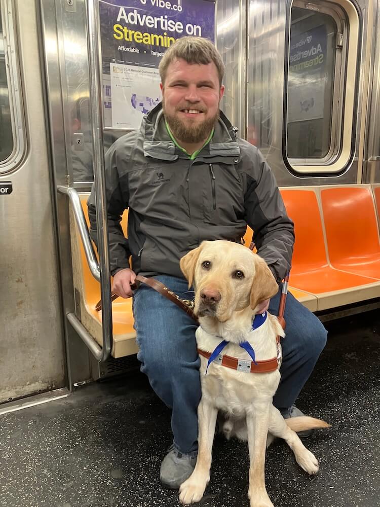 Austin sits on the orange seat of paratransit with Jimbo at his feet