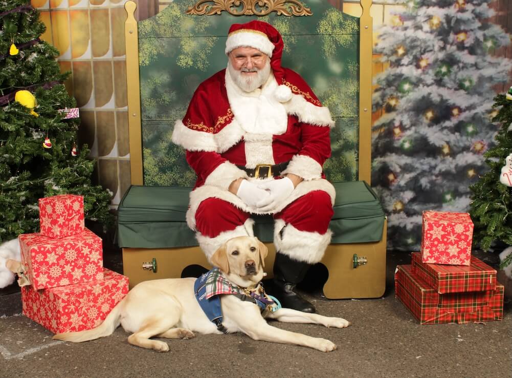 Jolly wears her Future Guide Dog jacket while in a down in front of Santa