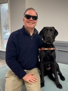 Doug and black Lab guide dog Deirdre, side by side for the indoor team portrait