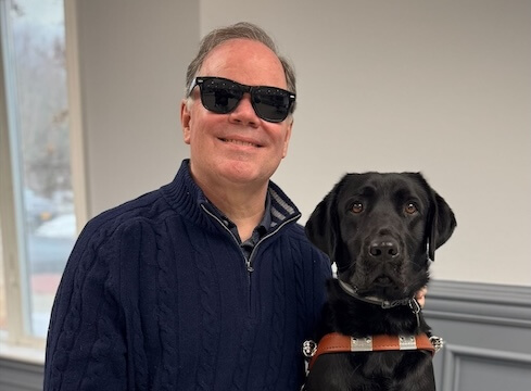 Doug and black Lab guide dog Deirdre, side by side for the indoor team portrait