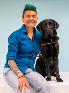 Damien and black Lab guide dog Whim pose for their graduate team portrait against a blue background.