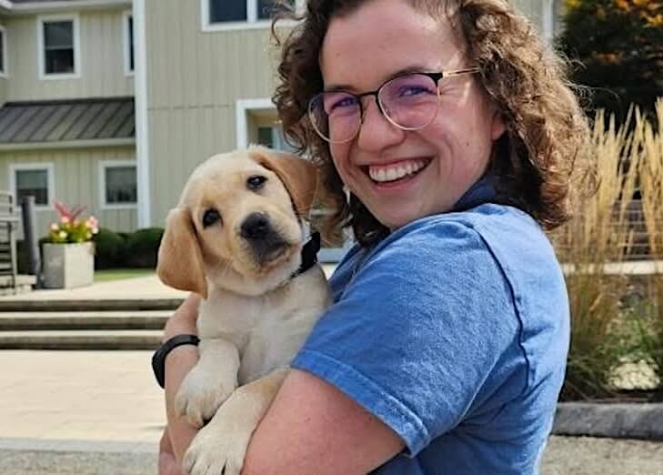 Raiser Steph holds adorable yellow Lab puppy Nessa who she will raise next.