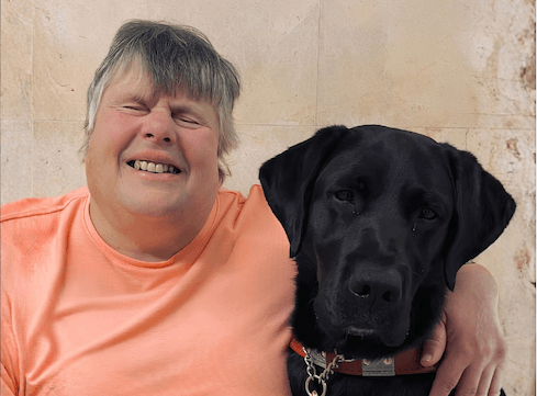 Katherine and black Lab guide dog Morgan sit side by side for their team portrait