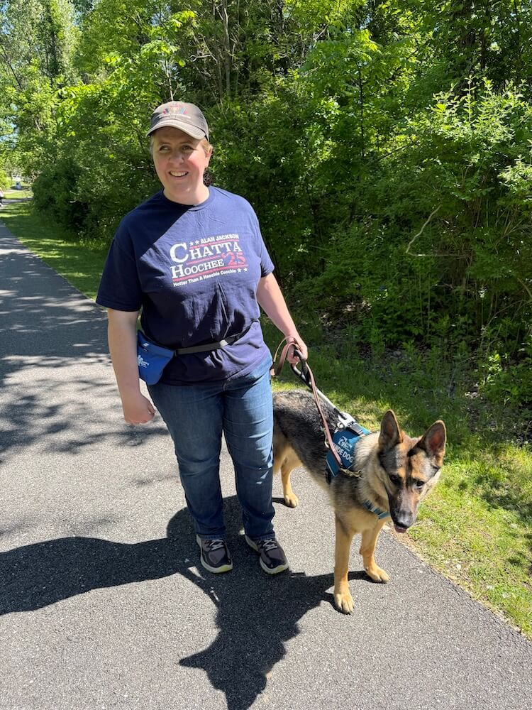April and German Shepherd Rose pause during a walk on a path adjacent to woods