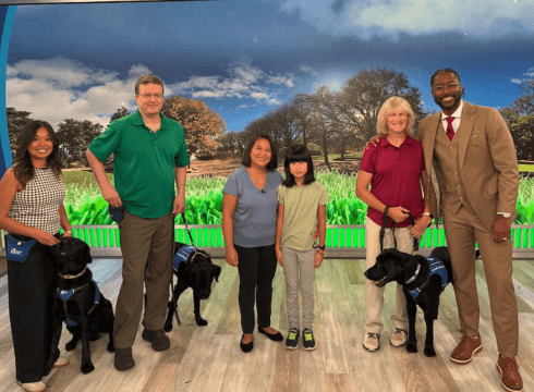 Raisers and dogs with hosts Gayle and Nate in front of segment backdrop