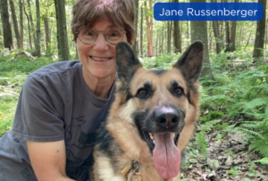 Jane Russenberger with a German Shepherd in a wooded area