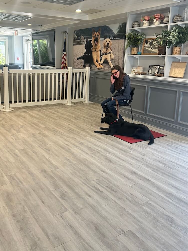 Kalia sits in Alumni hall during training while Bethany lies quietly on a red mat