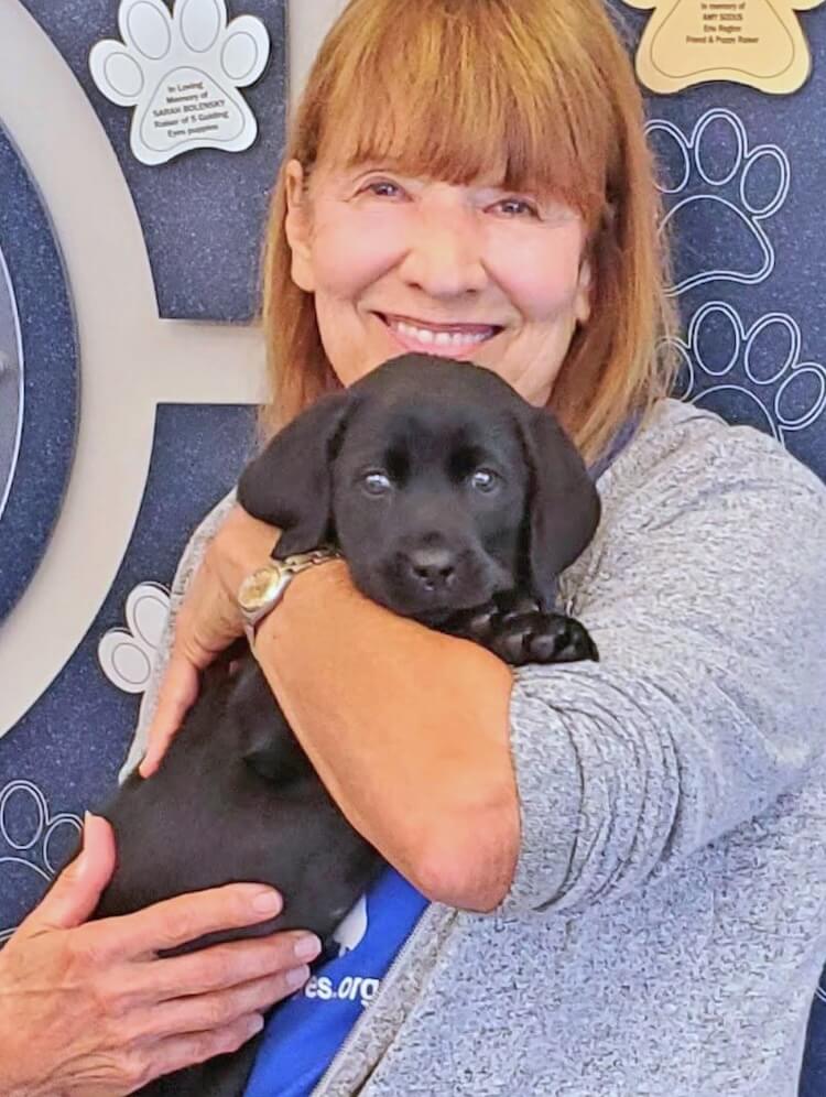 Raiser Susan holds puppy Mimi in the Patterson CDC lobby before taking her home to raise her