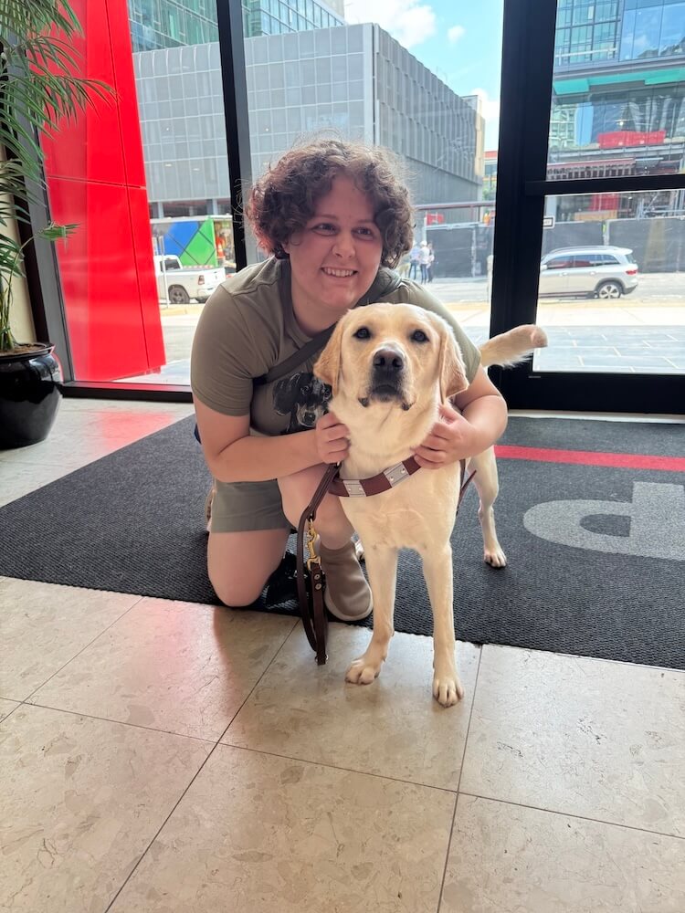 Franny kneels next to guide Tatum in the entrance of a city building