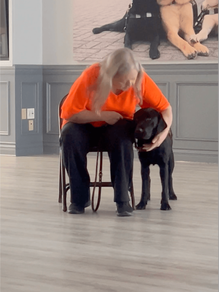 In Alumni Hall Gail sits and reaches her arm around Mimi to praise her for a positive behavior