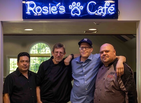 Under the blue neon sign for Rosie's Cafe stands Chef Rob and his team