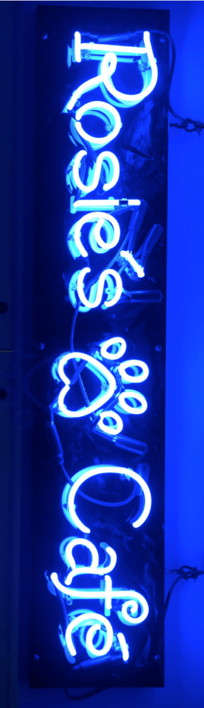the blue glow of Rosie's Cafe neon sign with a pawprint between the two words